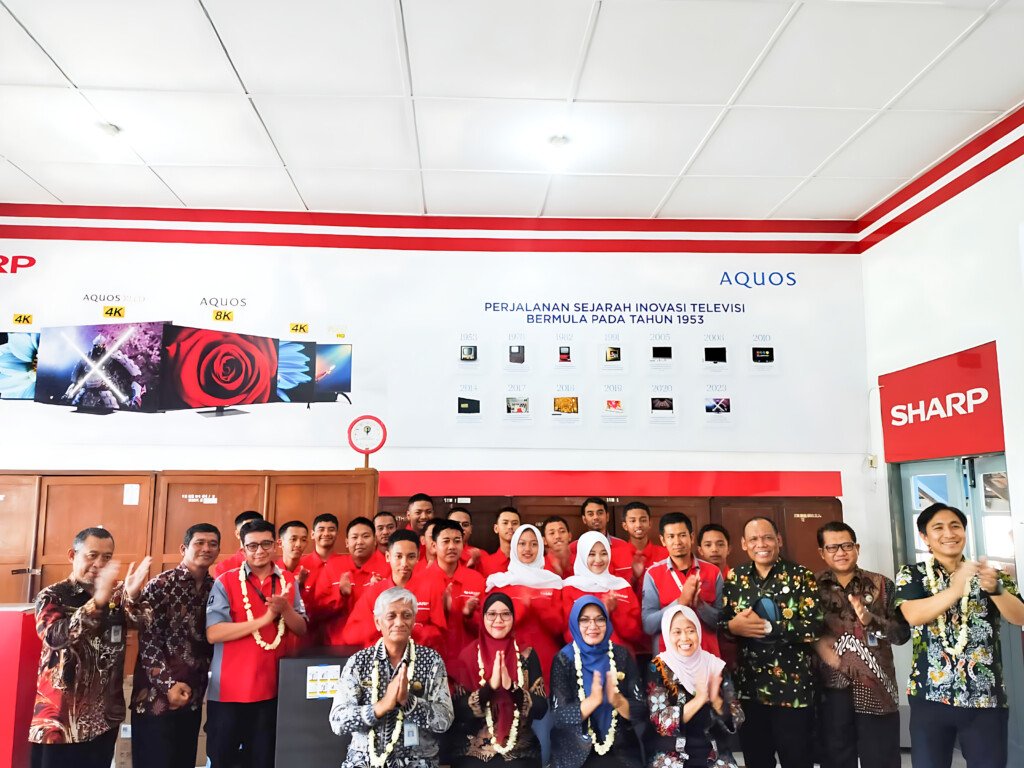 Perwakilan Sharp Indonesia, siswa program Sharp Class, serta perwakilan dari sekolah dan dinas terkait berfoto bersama. Latar belakang foto menampilkan sejarah inovasi televisi Sharp Aquos.