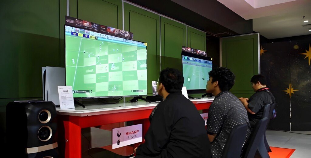 Penggemar Spurs bermain gim sepak bola menggunakan Sharp AQUOS LED TV dan speaker Sharp dengan kualitas suara jernih.