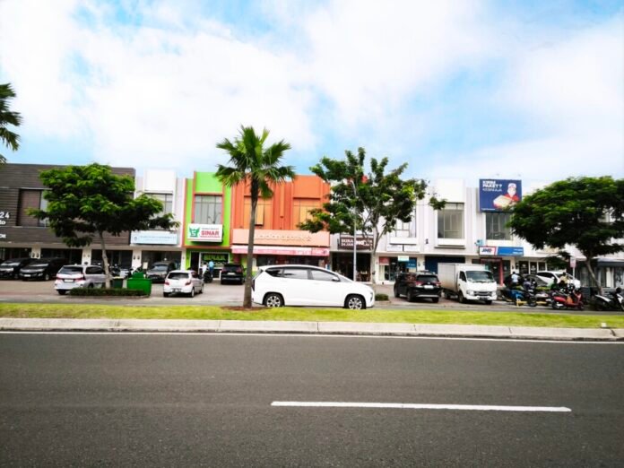 Pemandangan siang hari ruko Grand Boulevard Aniva Gading Serpong yang dipenuhi kendaraan dan aktivitas.