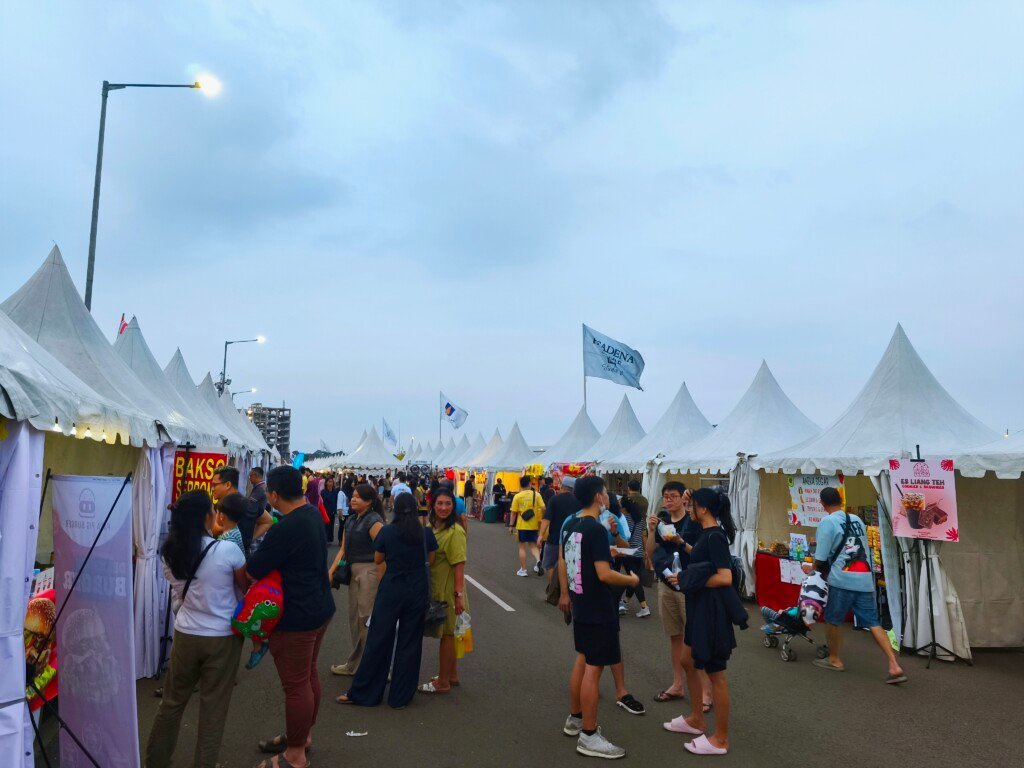 Suasana sore hari di area bazar dan pameran produk di Paramount Festival Kemerdekaan Gading Serpong, terlihat banyak tenda putih dan pengunjung yang berinteraksi.