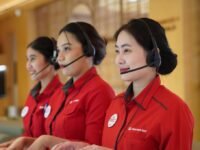 Tiga agen Contact Center Sinar Mas Land mengenakan headset dan seragam merah sedang melayani di Call SML 1500 765, layanan pelanggan properti 24 jam.