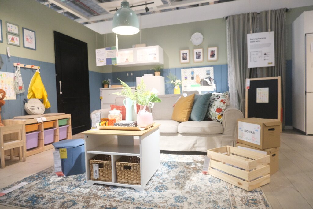 Contoh decluttering dan solusi penyimpanan minimalis dengan kotak donasi, peti kayu, dan furnitur multifungsi di ruang keluarga