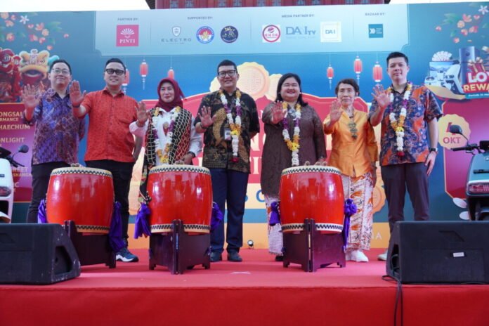 pembukaan-old-shanghai-mooncake-festival-bersama-pejabat-dki-jakarta-dan-pinti Tujuh tokoh, termasuk Kepala Dinas P3AP2 DKI Jakarta dan Ketua PINTI dr. Meta Agustina, berpose di atas panggung di samping dua drum besar saat acara Pembukaan Old Shanghai Sedayu City Mooncake Festival. Semua melambaikan tangan.