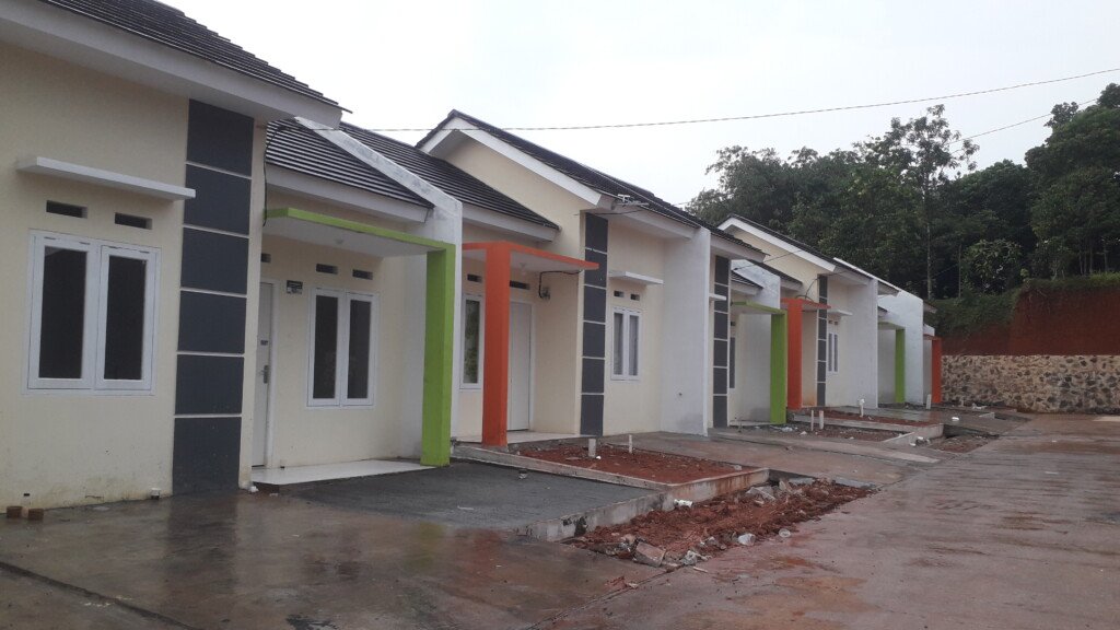 Pemandangan unit perumahan rakyat berwarna biru yang sedang dalam tahap pembangunan. Terlihat pekerja membawa gerobak, menandakan proyek rumah subsidi bagi MBR terus berjalan, program perumahan rakyat mbr
