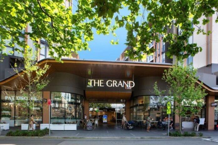 Tampak depan One Global Gallery Eastlakes atau The Grand dari One Global Capital di Australia dengan suasana area komersial yang hidup