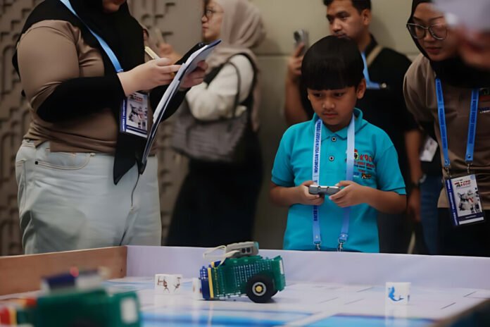 Seorang peserta muda KRON 2025 sedang fokus mengendalikan robot mini di arena kompetisi. Digital Hub Sinar Mas Land Kontes Robot Nusantara ini diadakan di ICE BSD City