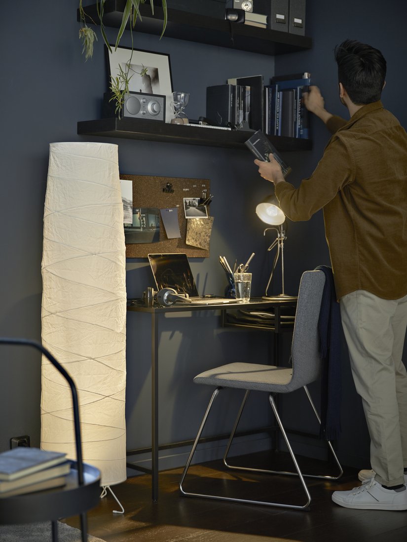 merapikan buku di rak dinding area kerja dari rumah