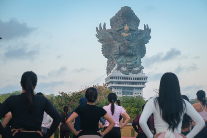 Peserta Morning Mat Pilates mengikuti sesi wellness outdoor di GWK Cultural Park Bali dengan latar Patung Garuda Wisnu Kencana
