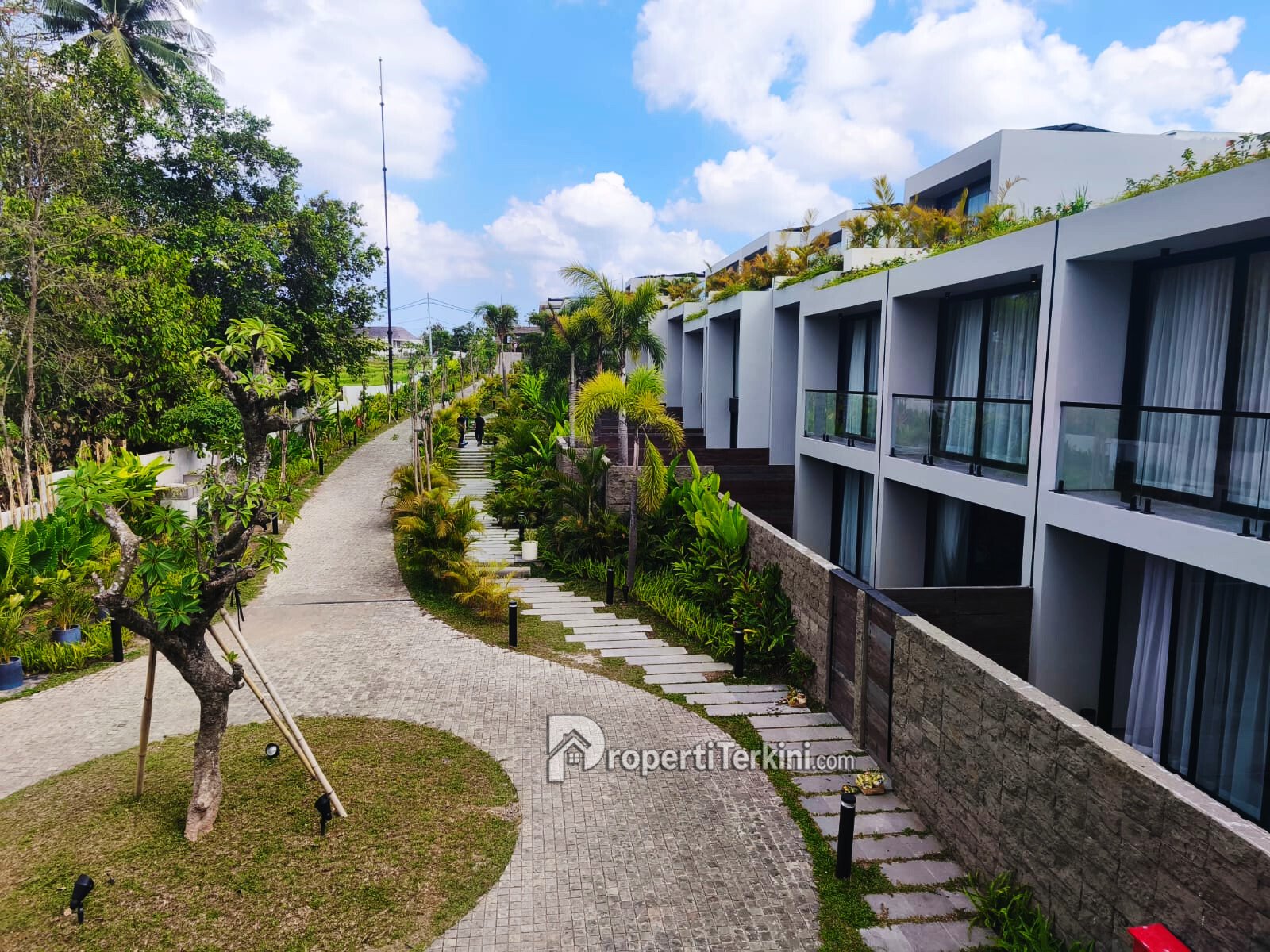 Koridor kawasan Ecoverse Nuanu Bali dengan deretan townhouse dan suite di lingkungan hijau berkonsep sustainable housing